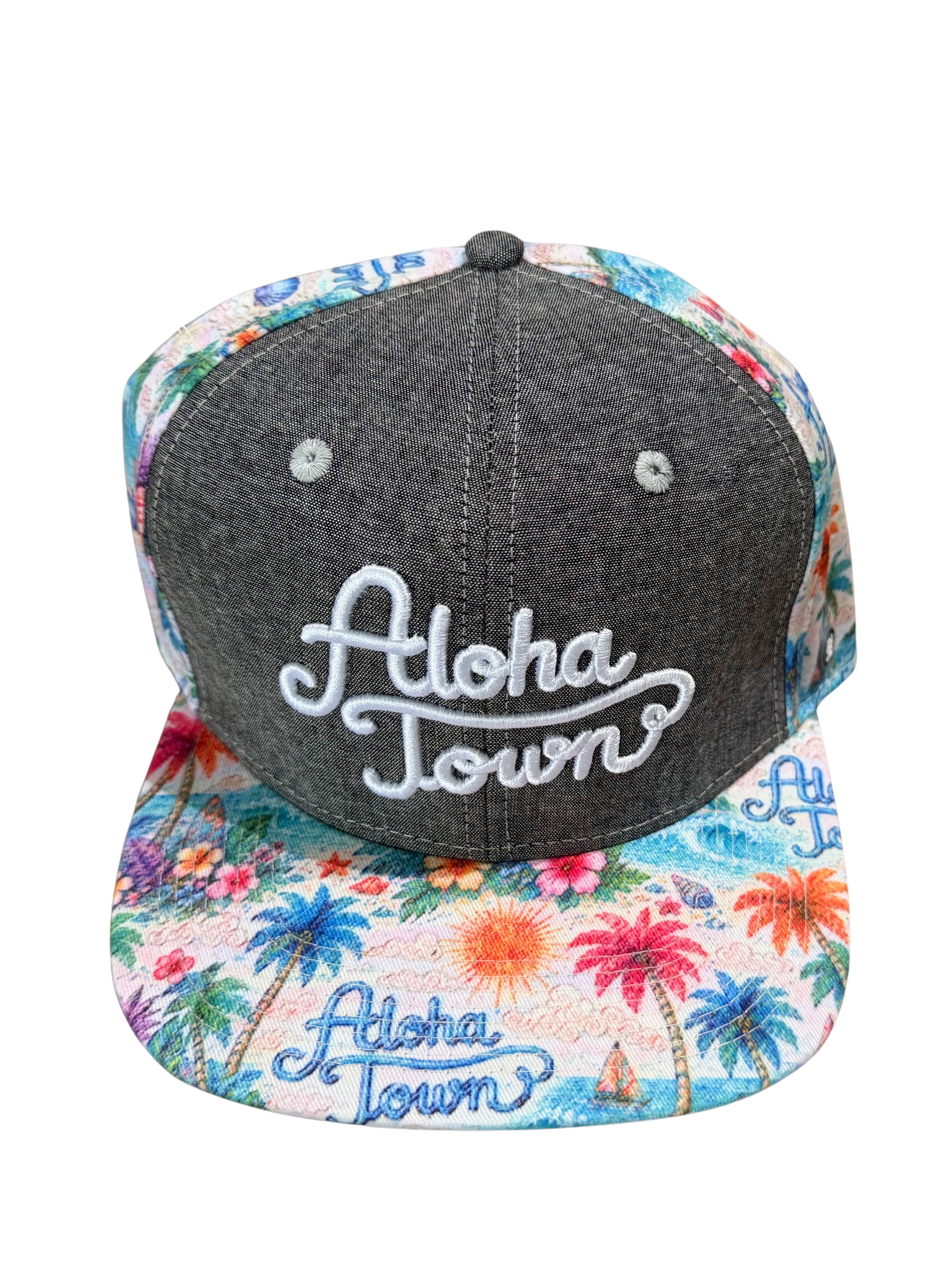 A snapback cap featuring a dark gray heather front panel with white embroidered 'Aloha Town' script, and a colorful tropical palm tree print on the brim and back panels.