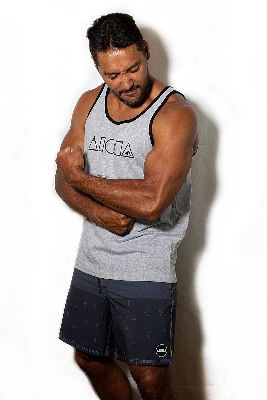 Man showing off his muscles wearing a Mauka to Makai Aloha Shapes® logo unisex tanktop