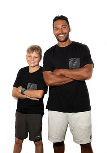 Teenage and adult man standing next to each other with arms folded both wearing Repeat Aloha Shapes® pocket tees in small and large sizes