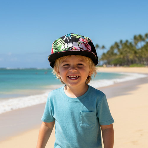 Child wearing Aloha Nights snapback backwards on beach