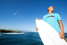 Young man holding a shortboard surfboard with an all black ALOHA Shapes ® logo decal sticker on it.