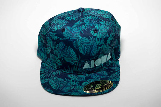 Adult flat brim snapback hat. Blue/green tropical taro leaf print fabric all over hat. Embroidered with light blue ALOHA Shapes ® logo