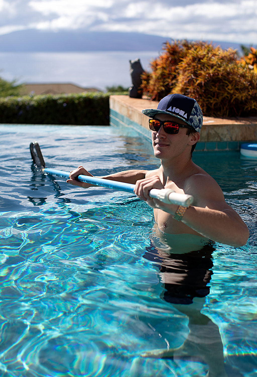 Young man in a swimming pool wearing an Aloha Shapes ® snapback hat