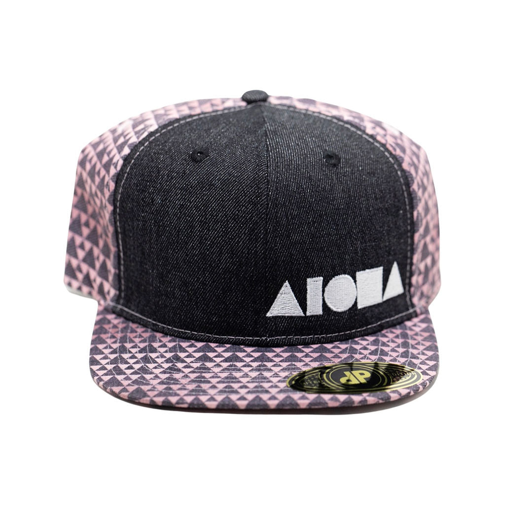 Adult flat brim snapback with black denim front panels and pink triangle pattern back panel and brim. Silver Aloha Shapes logo