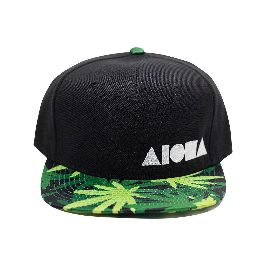 Black canvas flatbrim snapback with satin fabric print on brim with green pakalolo leaves and a white embroidered Aloha Shapes logo