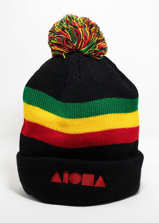 black knit cuffed beanie with red, yellow, green stripe around head and multi-color pompom on top. Embroidered with red Aloha Shapes logo.
