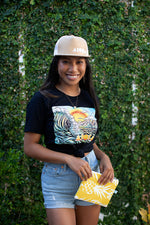Young woman wearing Black t-shirt featuring a Cartoon drawing of west side Maui beach surf spot designed in Big Island Hawaii and printed in Maui, Hawaii