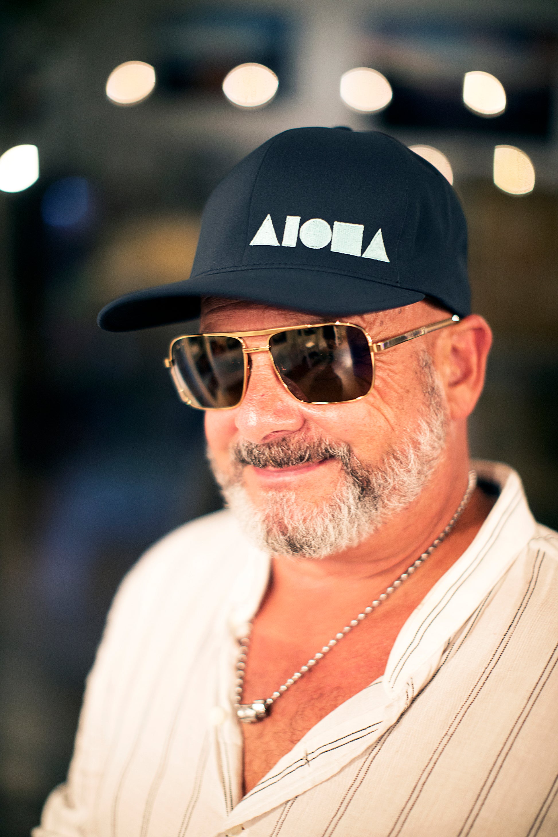Older gentleman wearing an ALOHA Shapes ® logo Flexfit hat and dark sunglasses