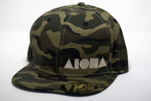 Adult flat brim snapback hat.  Military green/brown camo fabric all over hat. Embroidered with cream color ALOHA Shapes ® logo