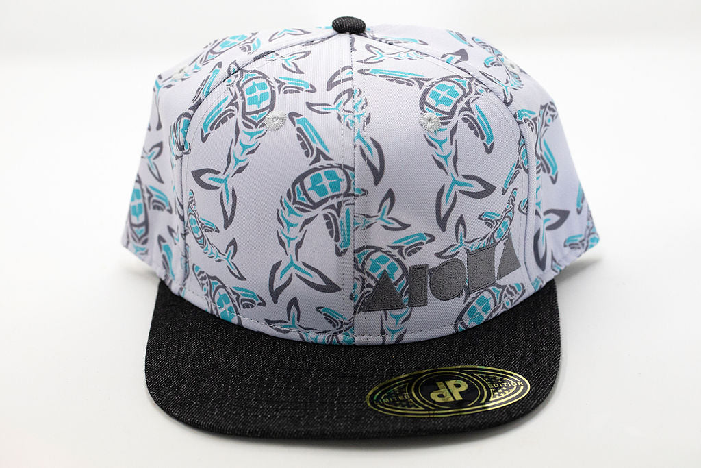 Adult flatbrim snapback hat printed with blue and grey totem style whale prints embroidered with grey Aloha Shapes® logo