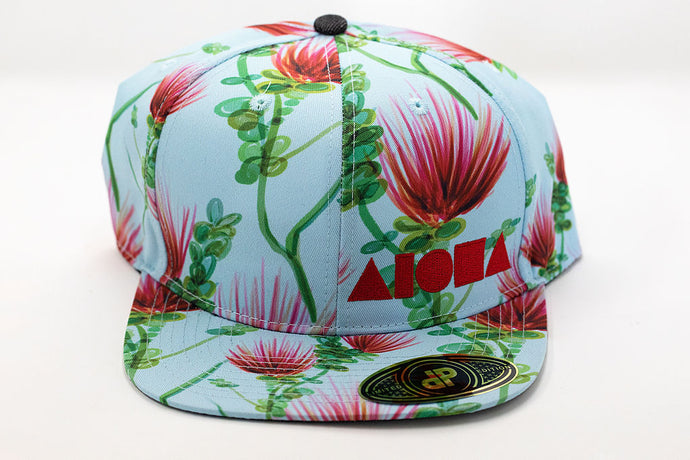 Baby blue flat brim snapback hat with red and green ohia Lehua floral print with embroidered red Aloha Shapes logo