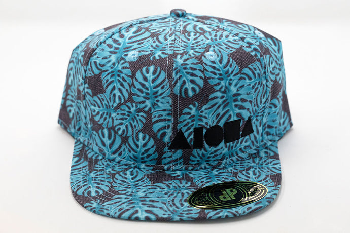 Blue monstera leaf tropical print fabric adult flat brim snapback hat embroidered with black Aloha Shapes logo