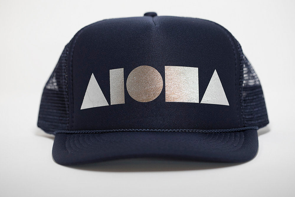 Adult foam trucker hat. Navy brim and front foam panel foil printed with silver ALOHA Shapes ® logo. Navy back mesh panels. 
