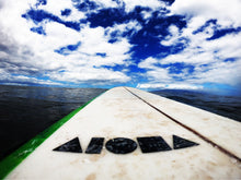 Surfboard with an all black ALOHA Shapes ® logo decal sticker in the ocean. 