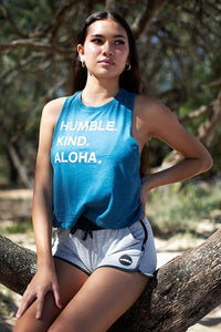 Woman sitting on a tree wearing Humble Kind Aloha womens crop tank top. 