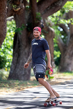 Person smiling riding a skateboard wearing an Aloha Island Shapes logo t-shirt