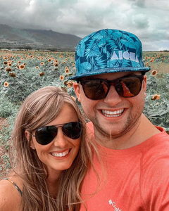 Couple posing in front of Maui sunflower field wearing Soley Aloha "Kalo" snapback hat