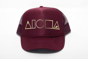 Maroon adult foam trucker hat printed with metallic gold Mauka to Makai Aloha Shapes logo