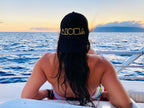 Person on a boat in Maui Hawaii watching the sunset with a Mauka to Makai trucker hat turned backwards