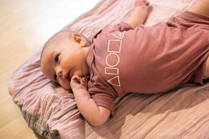 Baby wearing Mauka to Makai onesie in Mauve