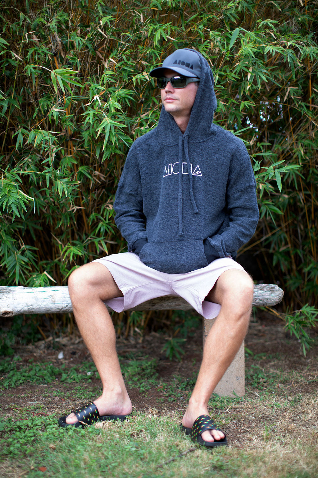 Man wearing Mauka to Makai hoodie and Repeat aloha Shapes slide slippahs