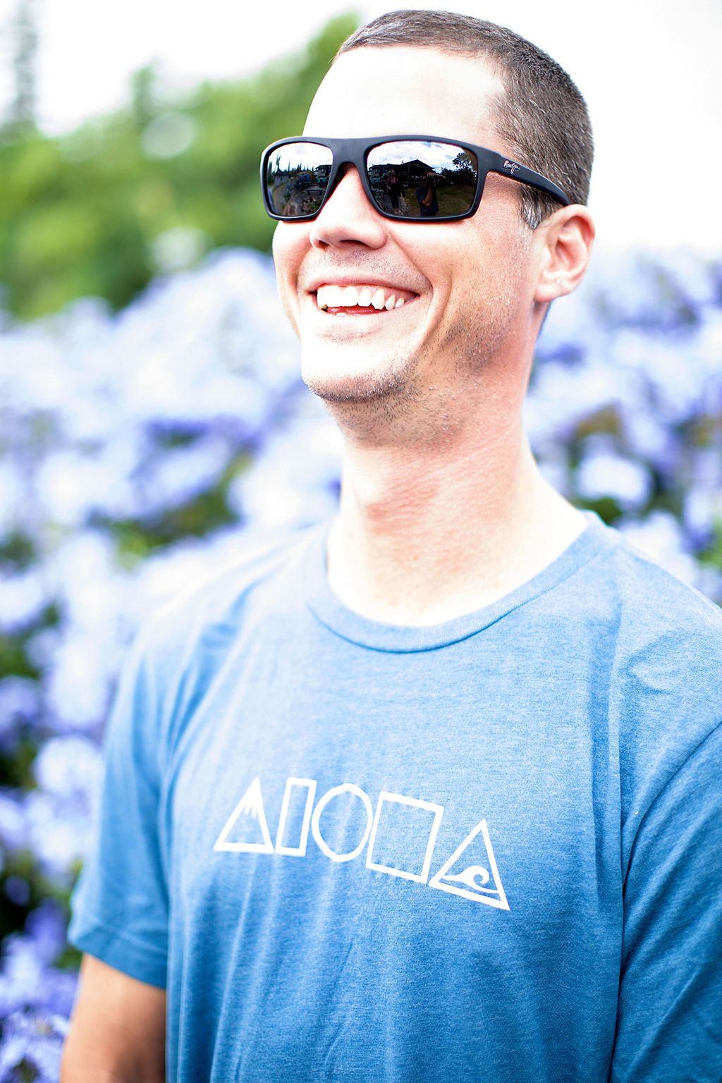 Man laughing wearing our Mauka to Makai Aloha Shapes sueded jersey tee in heather deep teal