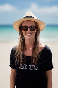 Woman wearing straw hat and black Mauka to Makai Aloha Shapes womens slouchy tee on a beach in Maui Hawaii  Edit alt text