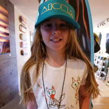 Young girl wearing youth Mauka to Makai trucker hat inside our boutique in Paia Maui