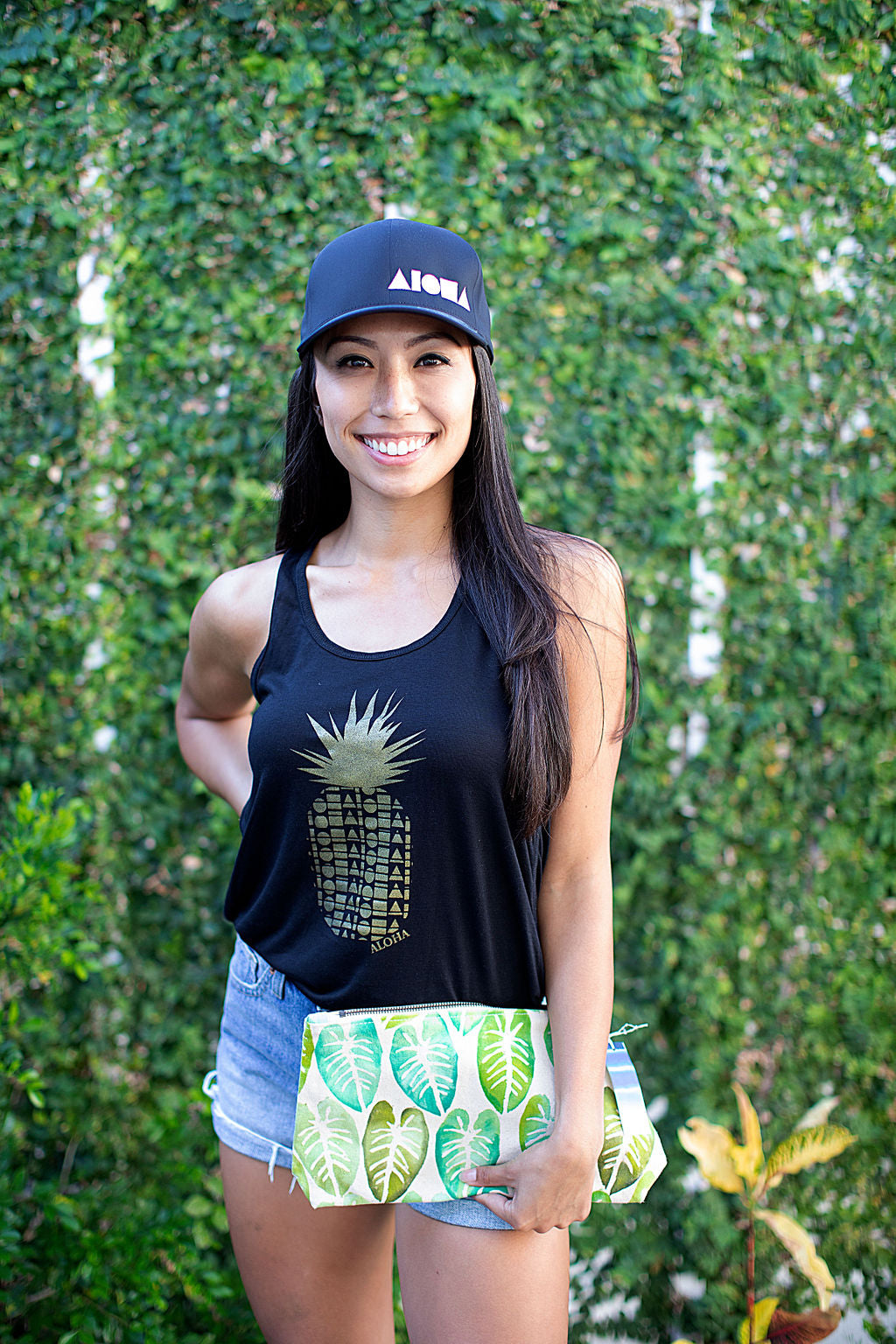 Smiling woman wearing Adult Flexfit curved bill hat. Black with white embroidered ALOHA Shapes ® logo. 