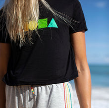 Closeup of Woman on beach in Maui wearing womens Rainbow Aloha Shapes® logo flowy crop tee