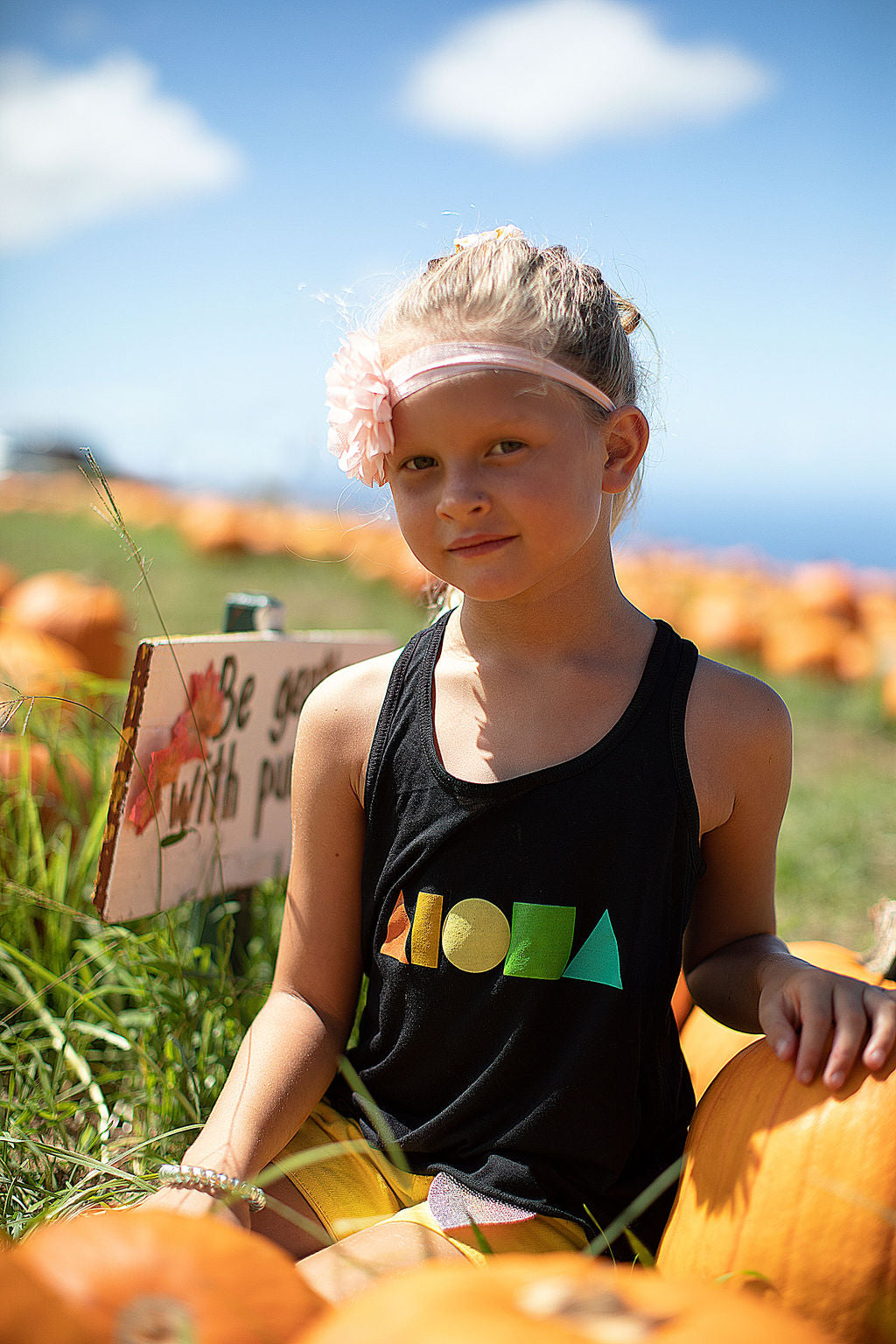 Young girl in pumpkin patch in upcountry Maui Hawaii wearing black Rainbow Aloha Shapes® youth racerback tank