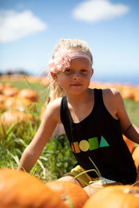 Young girl in pumpkin patch in upcountry Maui Hawaii wearing black Rainbow Aloha Shapes® youth racerback tank