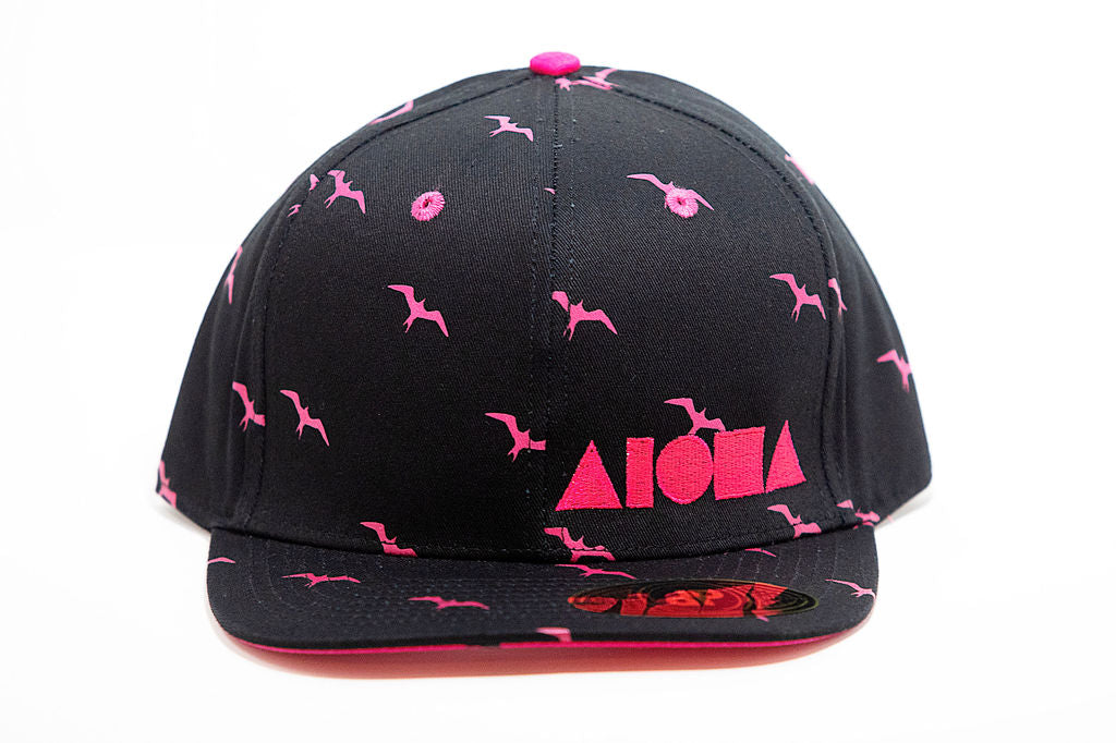 Adult flat brim snapback hat with black fabric and pink iwa bird pattern. Embroidered with neon pink Aloha Shapes ® logo