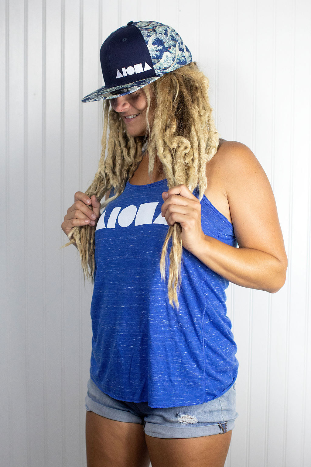 Blond dreadlocked girl wearing an Aloha Shapes ® racerback tank and "Waves for days" snapback hat