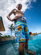 Young person wearing "Domes" Aloha Surf Shapes boardshorts standing in a pool in Maui Hawaii with hands on hips