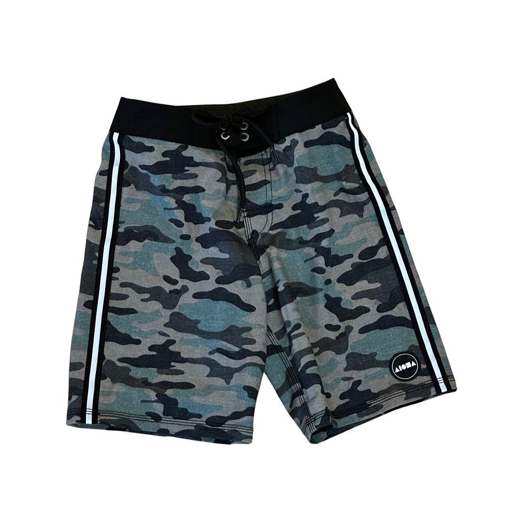 Youth surf boardshorts in a green/black camo print. Black and white striped taping down both side seams. Aloha Surf Shapes woven logo on bottom left leg