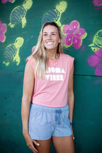Girl in Paia, Maui, Hawaii leaning against a wall wearing blue cotton "Abbey" Aloha Surf Shapes shorts