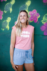 Girl in Paia, Maui, Hawaii leaning against a wall wearing blue cotton "Abbey" Aloha Surf Shapes shorts