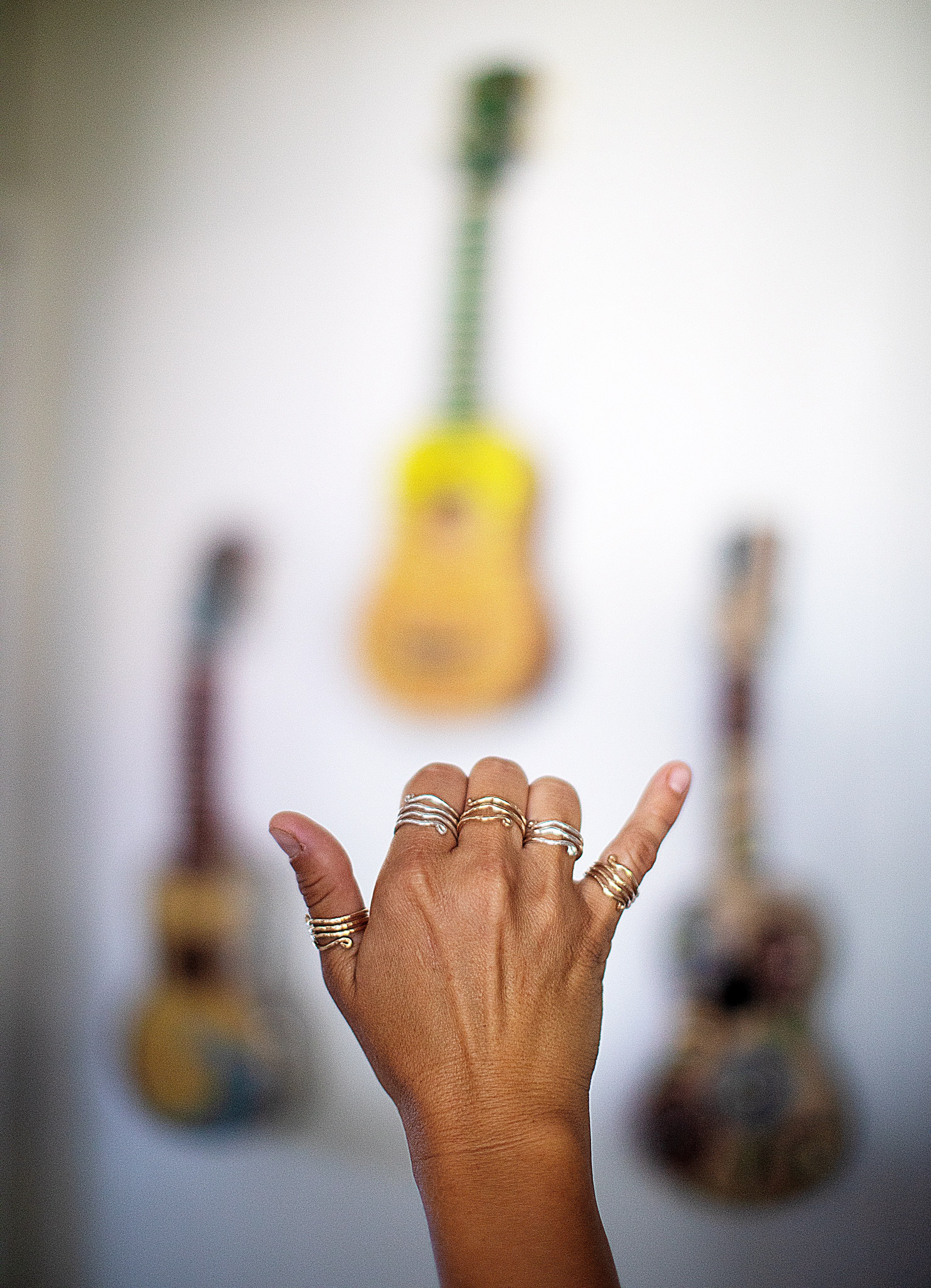 Hand throwing a Hawaiian shaka wearing assorted Wave Rings