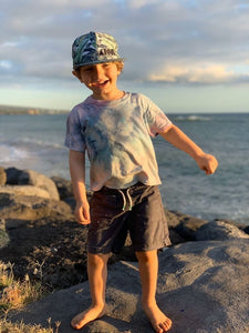 Happy young child near the ocean wearing a "Banana Bread" youth snapback hat
